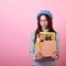 Dismissed french lady in a stylish beret hat, with a cardboard box in her hands on a pink background
