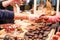 Display with assortment of dark and brown chocolate candies with different fillings. Seller`s hand picks some slice for buyer tes