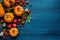 A display of autumn\\\'s bounty featuring a medley of orange mini pumpkins, leaves placed on a blue wooden surface. Fall