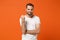 Displeased angry young man in casual white t-shirt posing isolated on bright orange wall background studio portrait