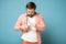 Displeased bearded man cleans his glasses from dust and dirt, wiping them with a shirt.  on a blue background.