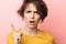 Displeased beautiful woman posing isolated over pink wall background