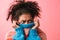 Displeased beautiful young african woman posing  over pink wall background covering face with sweater