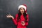 Displeased brunette woman in red blouse and christmas hat