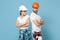 Displeased couple woman man in protective helmet hardhat isolated on blue background. Instruments accessories renovation