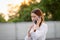 Displeased  and disappointed girl with a mobile phone stands in parking lot . In the evening the sunset was orange. copy space