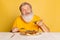 Displeased gray bearded man tasting italian pizza with cheese isolated on yellow studio background.