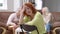 Displeased redhead woman sitting on chair shaking head talking as blurred cheerful friends laughing having fun at