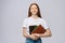 Displeased sad young woman college student holding book and crying on gray isolated background.