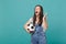 Displeased screaming woman football fan with soccer ball using mobile phone, spreading hands isolated on blue turquoise