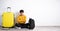 Displeased traveler guy with bad expression sits with suitcase isolated on white background