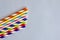 Disposable colorful striped paper cocktail sticks lie chaotically on light blue background. Eco friendly paper drinking straws.