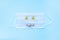 Disposable medical face mask with tablets and pills in a form of smiling mouth on the blue background. Kids healthcare concept