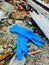 Disposable medical gloves on ground with other plastic trash on landfill. How to dispose used medical gloves right after