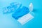 A disposable medical mask,one white bottle of antiseptic, a blue latex glove and Shoe covers on a blue background. The concept of