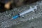 a disposable medical syringe lies on the street. The problem of drug addiction