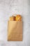 Disposable paper bag from a supermarket recyclable with whole baked loaves of bread flat lay on gray background with