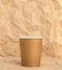 Disposable paper cup, on the background of crumpled kraft paper. Concept of using disposable eco-friendly tableware