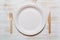 Disposable paper plate, wooden fork, and knife on wood background