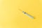 Disposable plastic syringe isolated on a yellow background.
