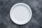 Disposable plastic tableware plates on dark background with copy space