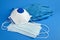 Disposable surgical face masks, white respirator and rubber gloves on blue background