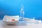 Disposable syringe with medication, capsules and pills on blue background