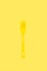 Disposable yellow plastic fork on a yellow background