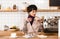 Dissatisfied businesswoman holding plate with macaroons while standing at bar counter in cafe.