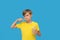 Dissatisfied teenage boy brushing his teeth isolated on blu background.