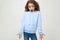 Dissatisfied teenager girl in a blue hoodie indignantly waving hands on a white background