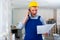 Dissatisfied worker in a protective helmet and blue overall discussing a repair plan on mobile phone