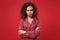 Dissatisfied young african american girl in pajamas homewear posing while resting at home isolated on red wall