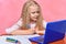 Distance learning. the child is studying at the laptop. schoolgirl writes with pencil. pink background
