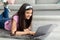 Distance learning concept. Joyful adolescent girl studying online, lying on soft carpet with laptop indoors