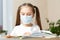 Distance learning online education.School girl in medical mask does homework o at home.Quarantine