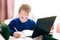 Distance learning online education. Schoolboy in a blue jacket studying at home with digital tablet and doing school homework.