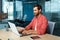 Distance Learning. A young man sitting at the desk in the office, studying online on a laptop