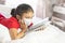 Distance schooling, learning online education. Girl wearing mask, studying at home with books and doing school homework. Laying on