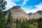 Distance view of Checkerboard Mesa in Zion NP with forest in foreground and blue cloudy sky