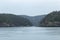 Distant cliffs across a large body of water covered in tall green trees