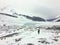 A distant faraway view of a female hiker alone walking through the vast winter landscape towards the athabasca glacier