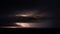 Distant lightning and dark storm clouds over the sea