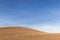 A distant, lonely tree on a bare hill, beneath a blue sky with white clouds