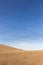 A distant, lonely tree on a bare hill, beneath a blue sky with white clouds