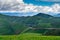 Distant mountains, blue sky and white clouds, green grassland full of wild flowers