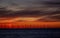 A distant off shore windfarm silhouetted against a vivid sunrise.