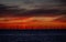 A distant off shore windfarm silhouetted against a vivid sunrise.