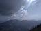 A distant panoramic rare view of mountains with dark clouds in blue sky