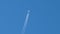 Distant passenger jet plane flying on high altitude on clear blue sky leaving white smoke trace of contrail behind. Air